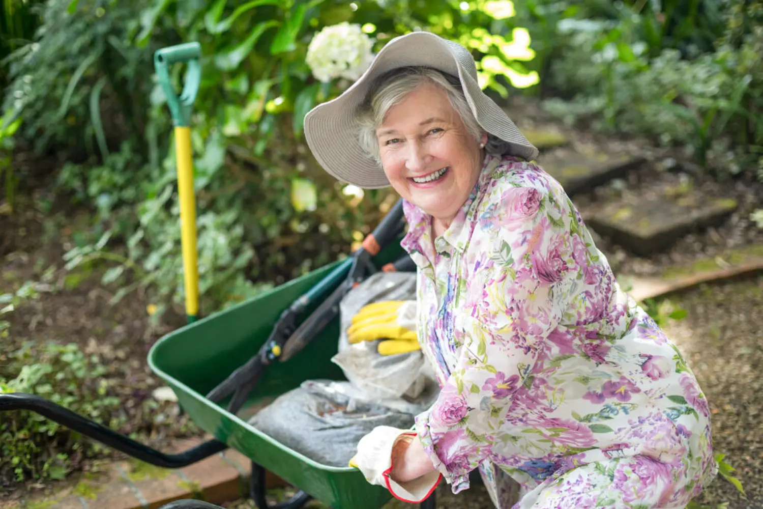 Porträt einer älteren Frau mit Schubkarre im Garten. (Ziemlich bester Ruhestand)